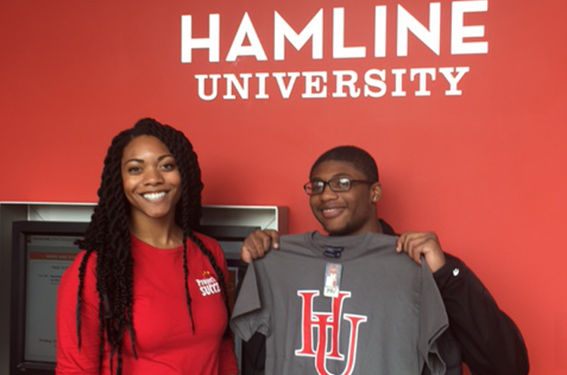 PS student and facilitator posing in front of Hamline University sign.