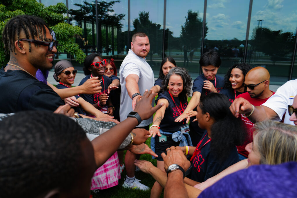 Students and PS staff huddle for a team cheer