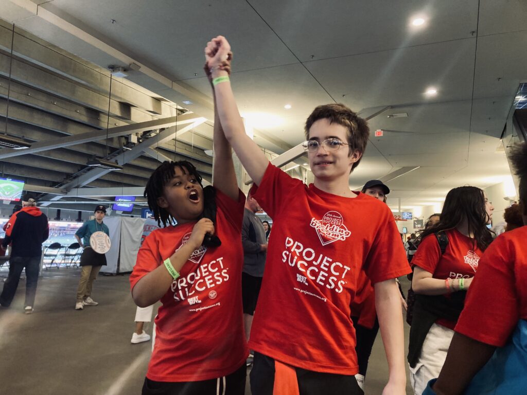 Two students with hands in the air.