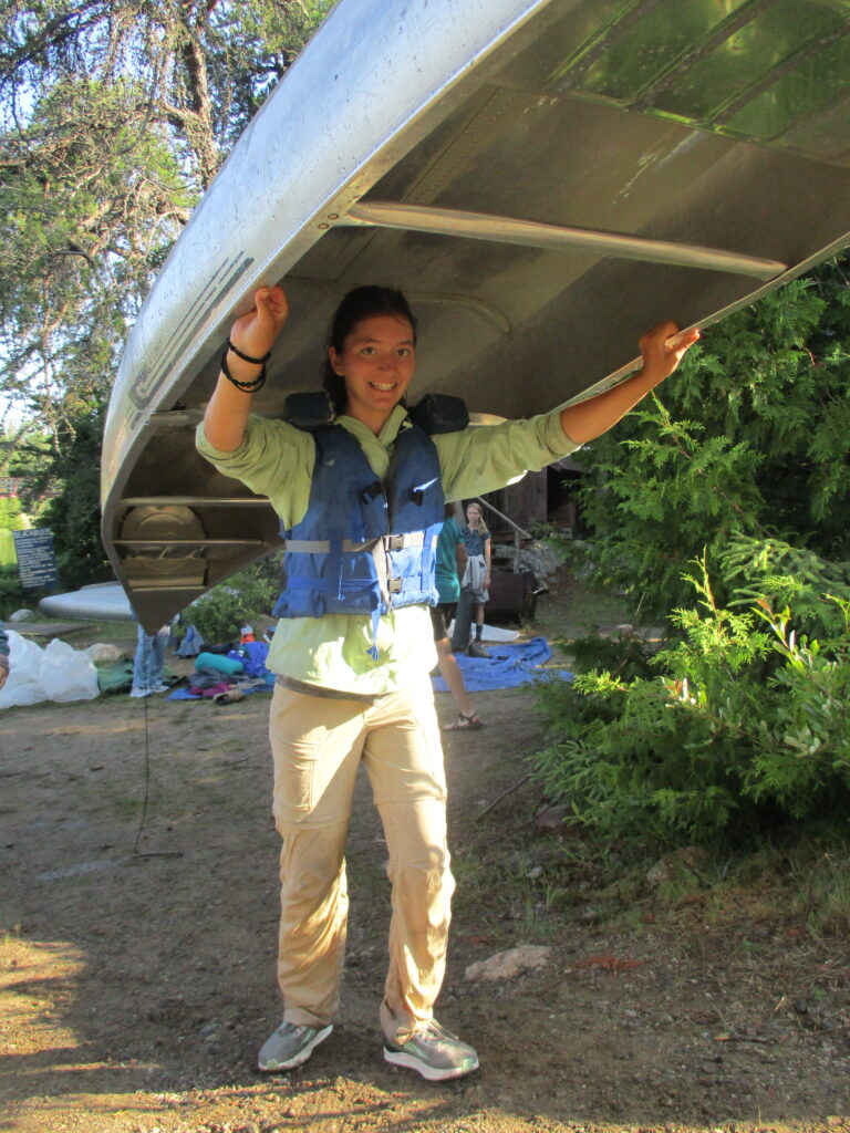 A student portaging a canoe.