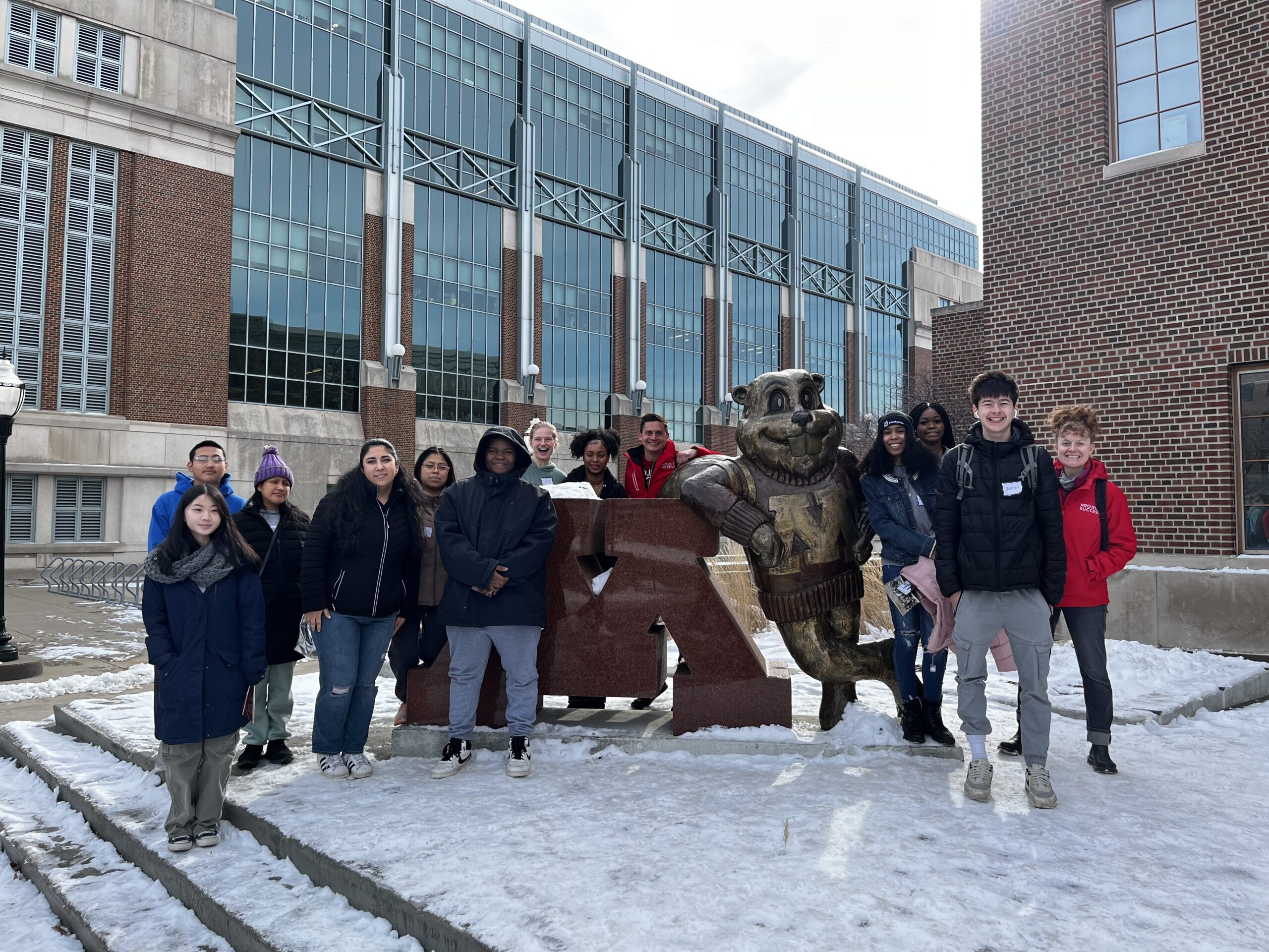 Group of PS students and staff gather around a goldy the gopher statue